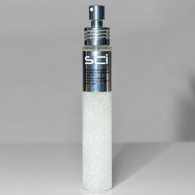 A cylindrical cosmetic bottle filled with sparkling white powder or glitter, featuring a metallic silver pump and a silver label with the brand name 'sci'.