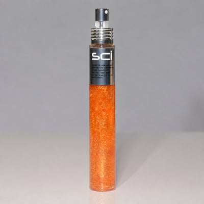 SCI Smooth Glittery Hair Spray in a clear cylindrical bottle filled with shimmering orange glitter, featuring a black and silver spray nozzle, set against a neutral gray background.